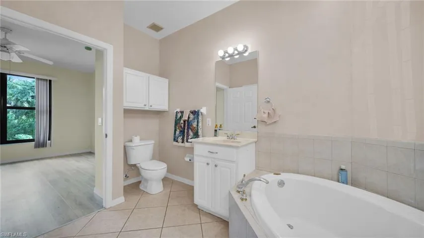 Full bathroom featuring light tile patterned flooring, a bath, vanity, and ceiling fan