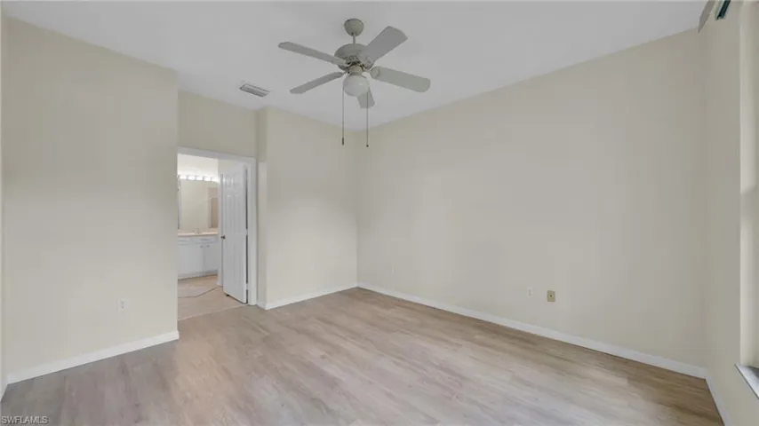 Unfurnished bedroom with light wood-style floors, a ceiling fan, and ensuite bathroom