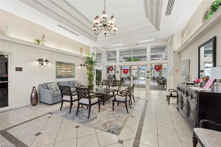 Dining space featuring inlaid floor details, a tray ceiling, a chandelier, light tile patterned floors, and a high ceiling