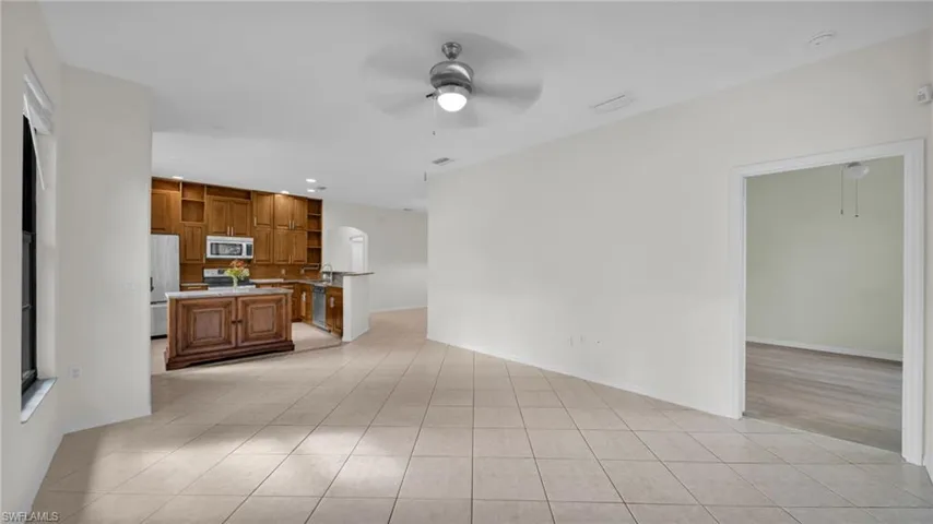 Unfurnished living room featuring ceiling fan, light tile patterned floors, recessed lighting, and arched walkways