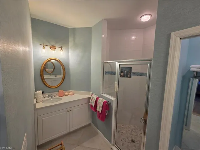 Full bath featuring vanity, a shower stall, and light tile patterned flooring