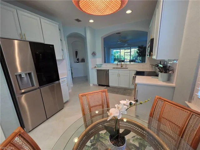 Kitchen with appliances with stainless steel finishes, white cabinetry, recessed lighting, arched walkways, and ceiling fan