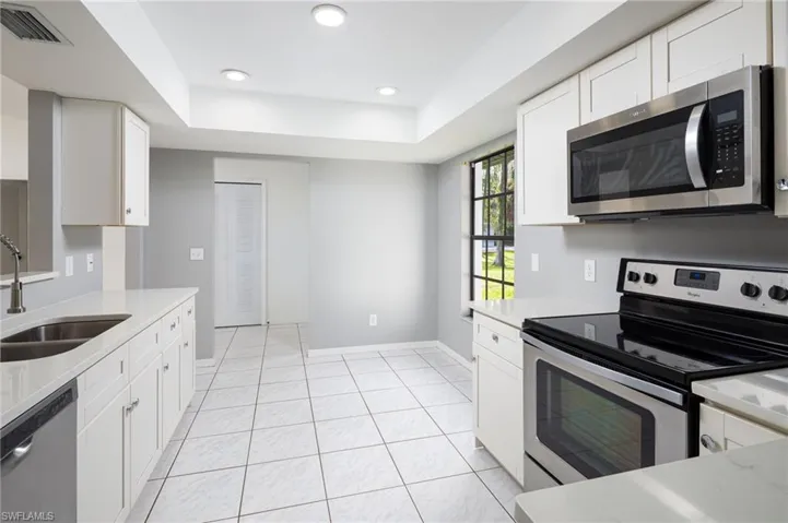 Kitchen featuring appliances with stainless steel finishes, white cabinets, quartz countertops, light tile patterned floors, and recessed lighting