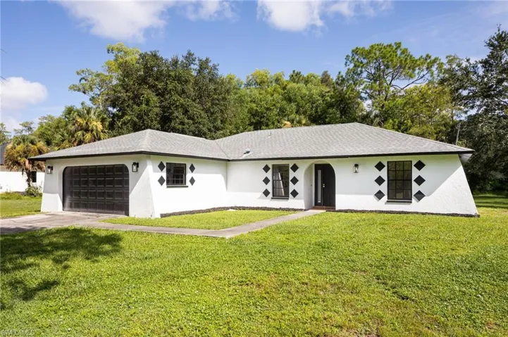 Ranch-style home with an attached garage, front yard, stucco siding, and concrete driveway
