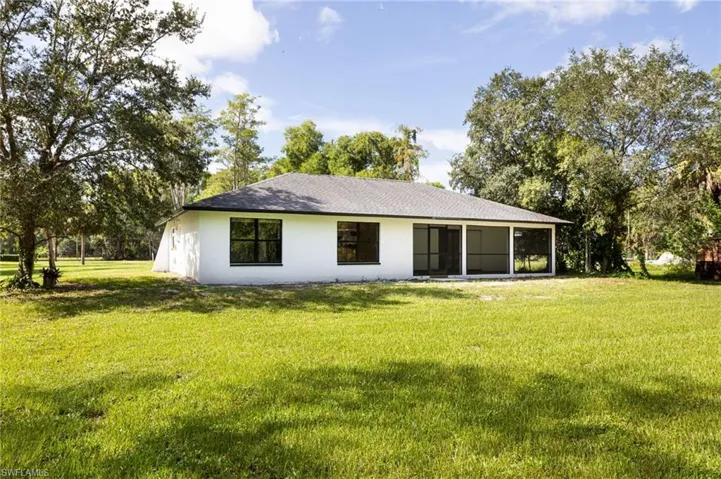 Back of property featuring a yard, a sunroom, and stucco siding