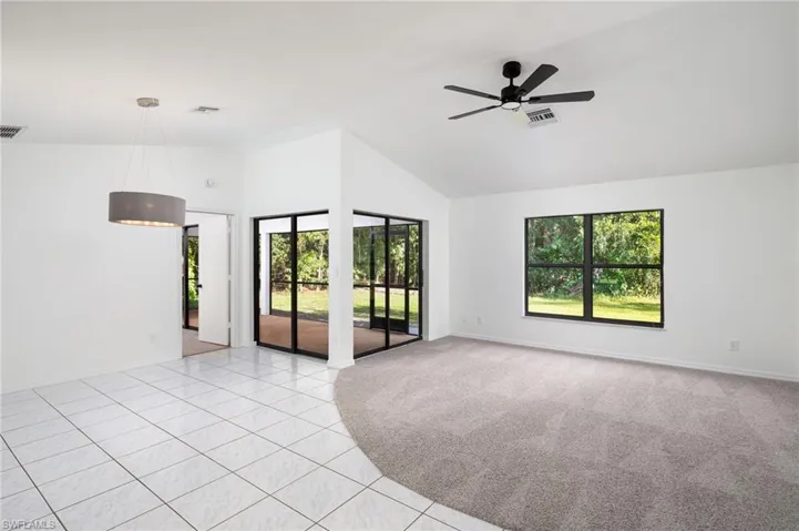 Living/Dining Area with light tile patterned flooring, high vaulted ceiling, new carpeting, ceiling fan and dining light fixture