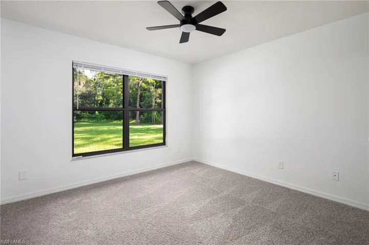 Guest bedroom featuring new carpet flooring and a ceiling fan