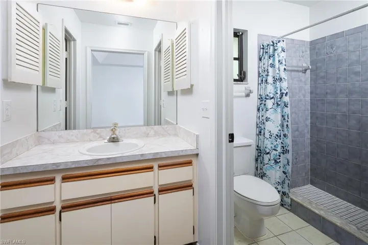 Full bath featuring vanity, light tile patterned floors, and a shower stall...ready for your personal touches.