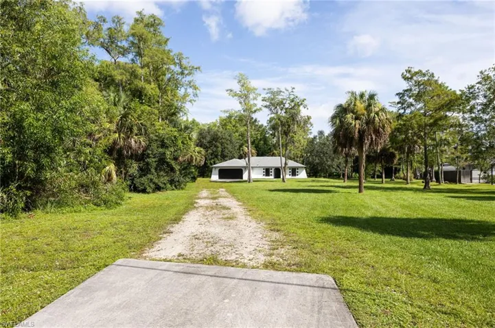 View of front of home with dirt driveway and a front lawn