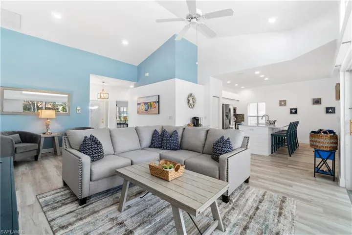 Living area featuring high vaulted ceiling, light wood-style flooring, and a wealth of natural light