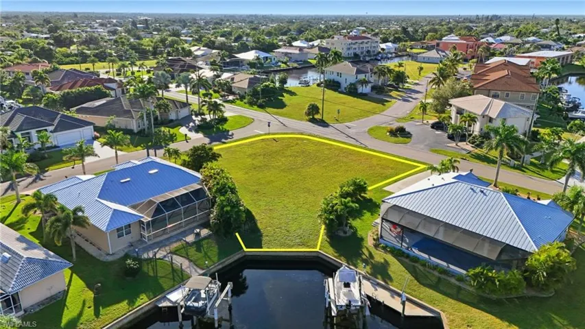 Aerial view of residential area featuring property boundaries highlighted and a nearby body of water
