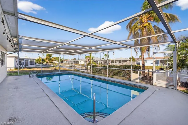 Outdoor pool featuring a sunroom, glass enclosure, a residential view, and a patio