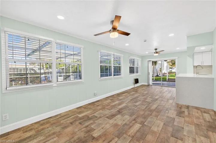 Unfurnished living room with light wood-style flooring, recessed lighting, a ceiling fan, and wooden walls