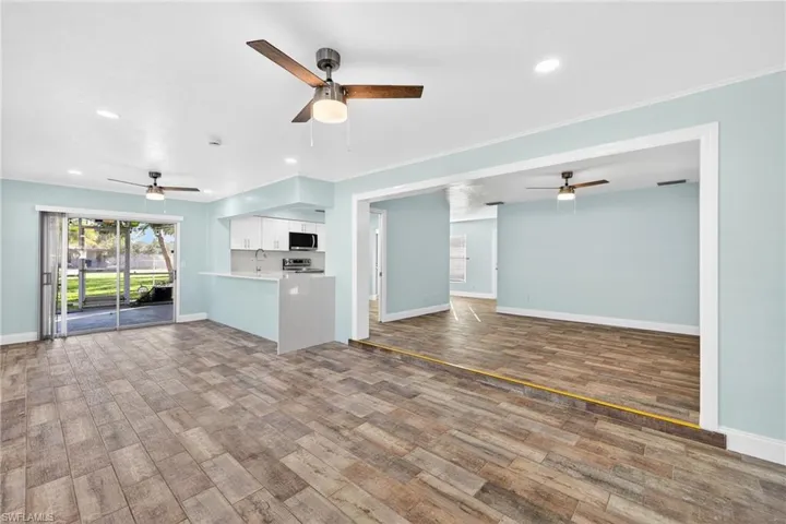 Unfurnished living room with ceiling fan, dark wood-style flooring, recessed lighting, plenty of natural light, and ornamental molding