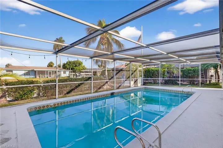 View of swimming pool featuring glass enclosure, a patio, and a sunroom
