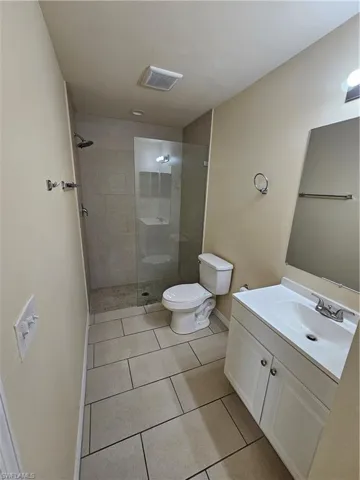 Bathroom with vanity, a tile shower, and light tile patterned floors