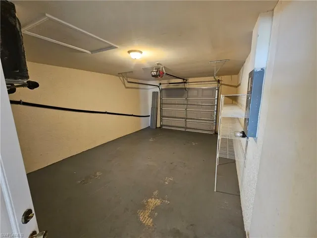 Garage featuring electric panel and a garage door opener