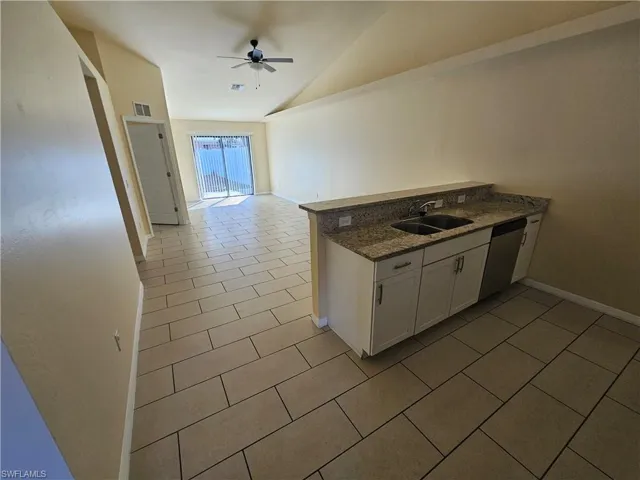 Kitchen with white cabinetry, a peninsula, dark stone counters, light tile patterned floors, and ceiling fan