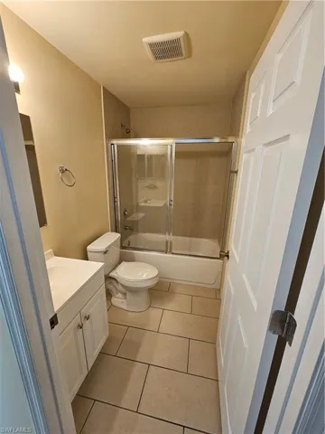 Full bathroom featuring shower / bath combination with glass door, vanity, and light tile patterned floors