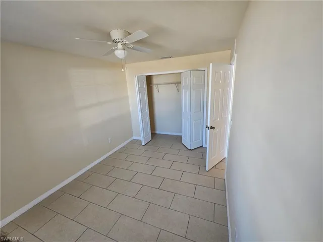Unfurnished bedroom featuring a closet, a ceiling fan, and light tile patterned flooring
