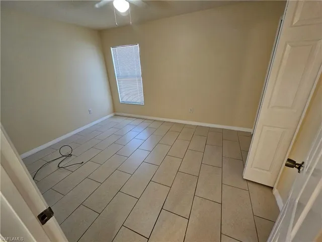 Empty room featuring baseboards and a ceiling fan
