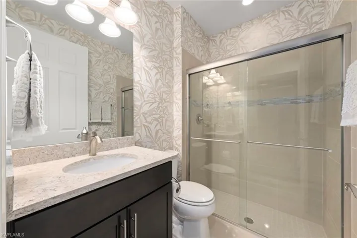 Bathroom featuring vanity, a shower stall, wallpapered walls, and recessed lighting