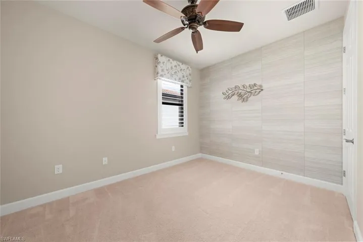 2nd bedroom with ceiling fan and tile wallpapered  walls