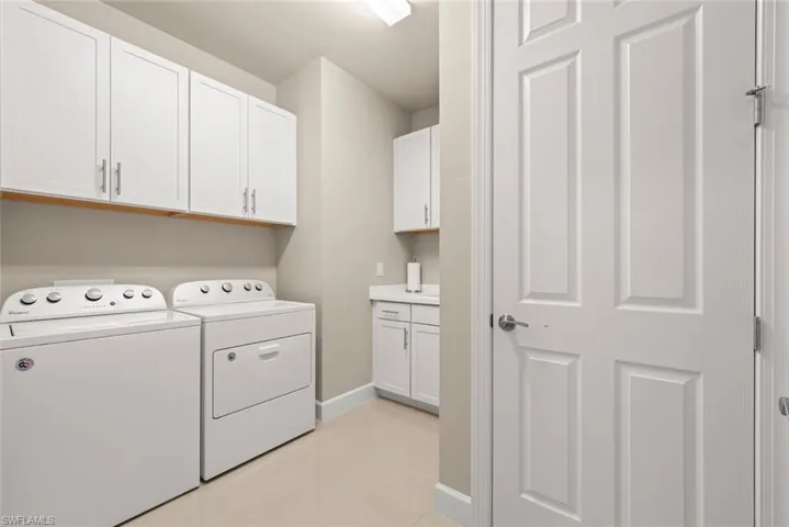 Laundry room with washer and dryer, cabinet space, and light tile patterned flooring and closet