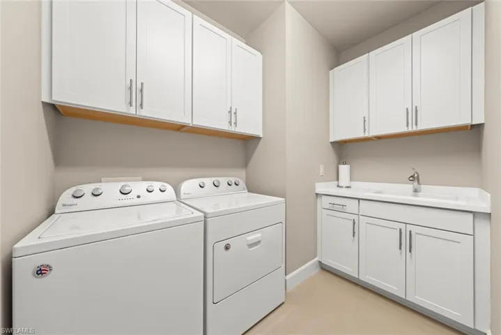 Laundry room featuring light tile patterned floors, washer and clothes dryer, and cabinet space