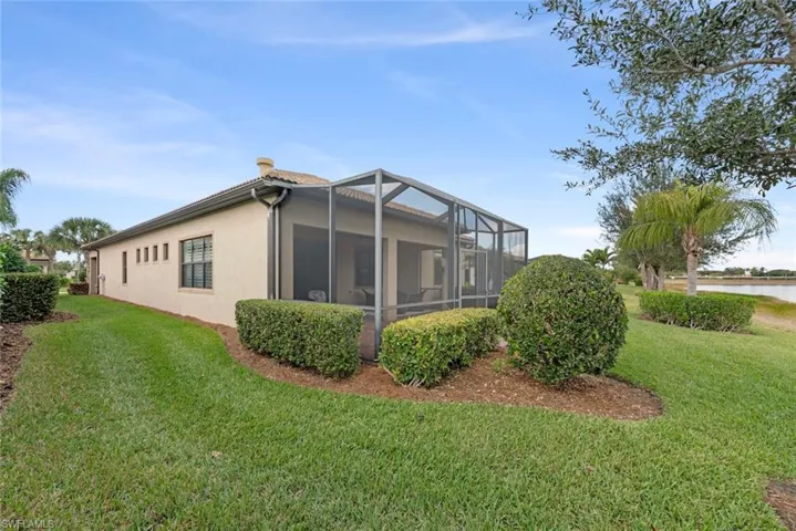 View of side of home with  yard, screened  enclosure, stucco siding, and a water view