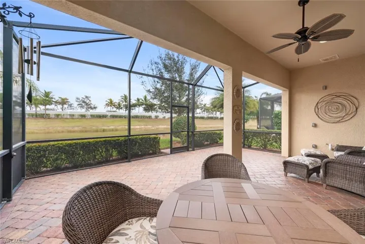 View of patio / terrace featuring, a water view, enclosure, ceiling fan, and outdoor dining area