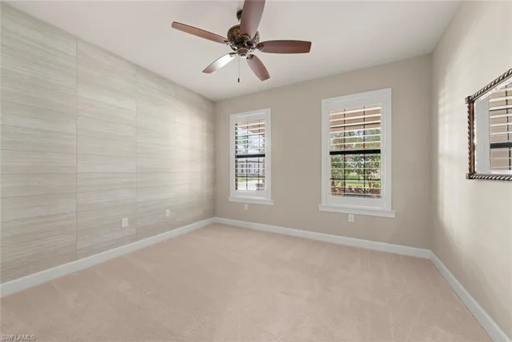First bedroom with light colored carpet and ceiling fan