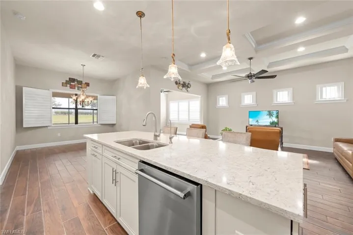 Kitchen with open floor plan, white cabinetry, stainless  appliances steel dishwasher,  tiled floors, and light quartz countertops