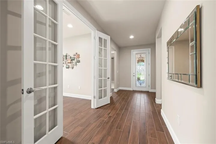 Hallway featuring   glass doors into Office,  tiled floors, and recessed lighting
