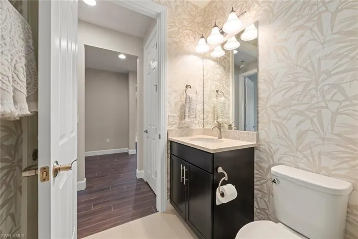 Half bath with vanity, with tile finish floors, wallpapered walls, and recessed lighting