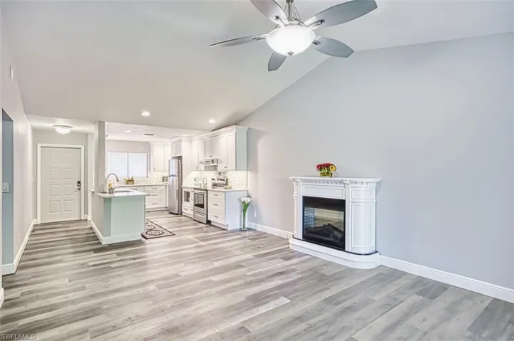 Living room with a multi sided fireplace, recessed lighting, light wood-type flooring, lofted ceiling, and ceiling fan