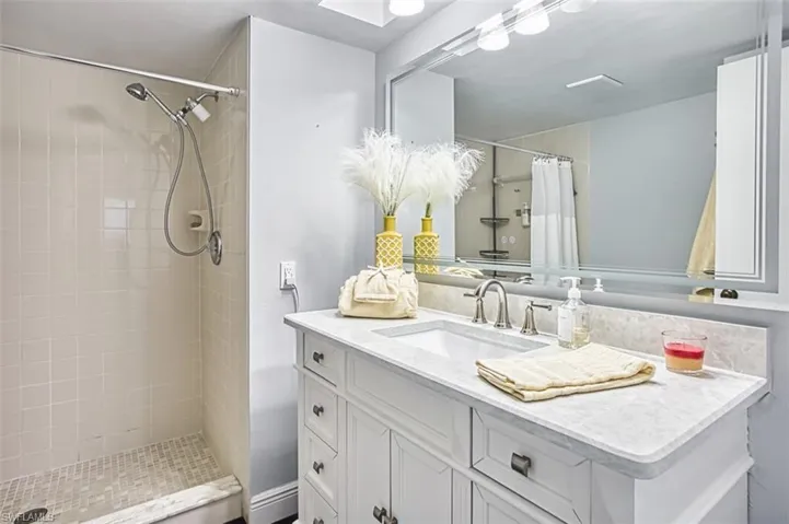 Bathroom featuring a shower stall, vanity, and a skylight