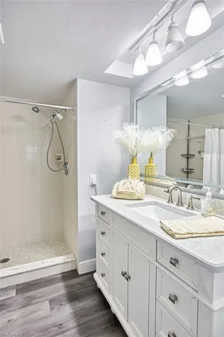 Full bathroom with vanity, a stall shower, dark wood-style floors, and a textured ceiling
