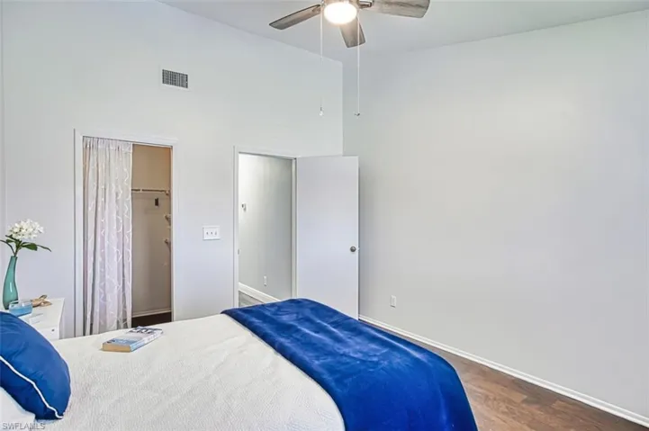Bedroom with wood finished floors, ceiling fan, a towering ceiling, and a closet