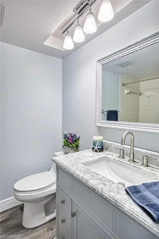 Bathroom with a textured ceiling, vanity, dark wood-type flooring, and tiled shower