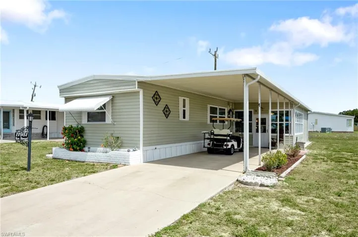 Manufactured / mobile home featuring driveway, a front lawn, and a carport