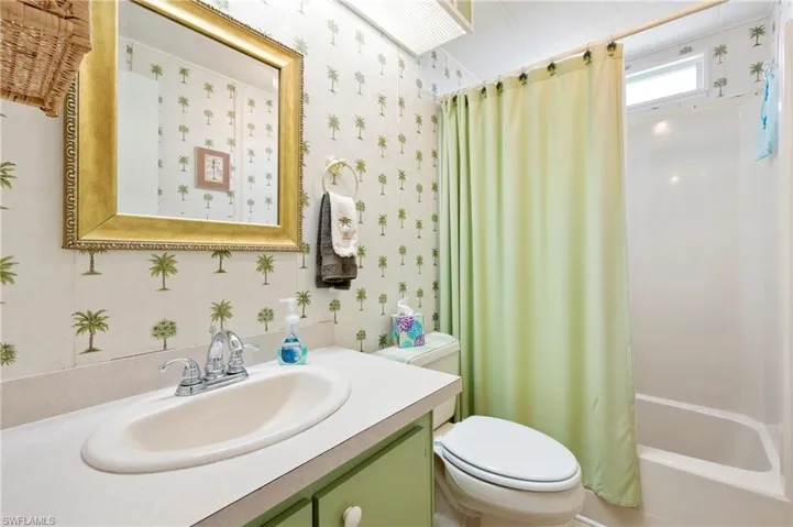 Full bath featuring toilet, wallpapered walls, vanity, and shower / bathtub combination with curtain