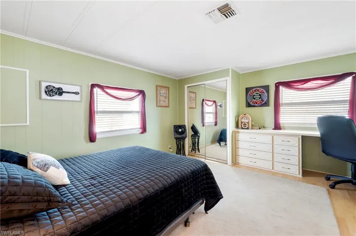 Bedroom with crown molding, an office area, wood finished floors, and a closet