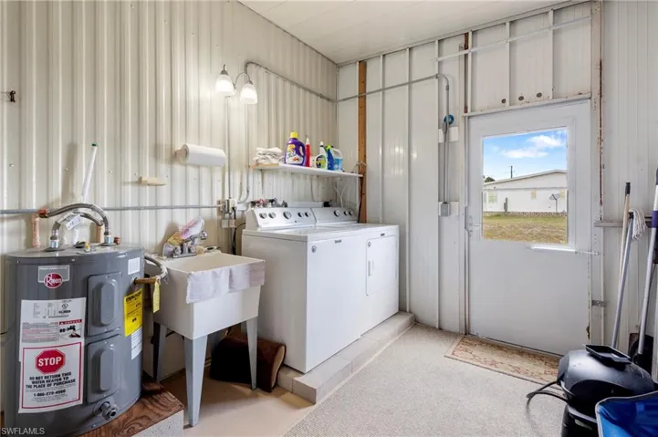Laundry room featuring electric water heater, washer and clothes dryer, and light colored carpet