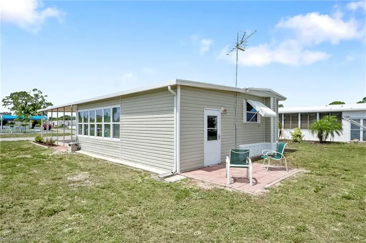 Back of property with a patio, a lawn, and a sunroom