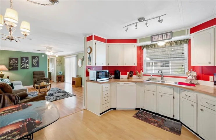 Kitchen with dishwasher, a sink, light wood-style flooring, open floor plan, and white cabinetry