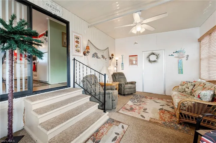 Living area featuring ceiling fan and stairs
