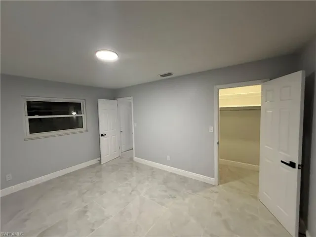 Unfurnished bedroom featuring a spacious closet and baseboards