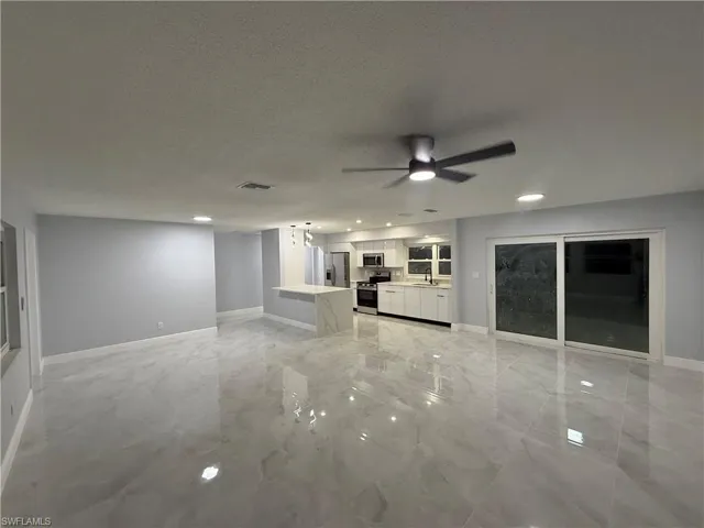 Unfurnished living room featuring a ceiling fan, a textured ceiling, light marble finish floors, and recessed lighting