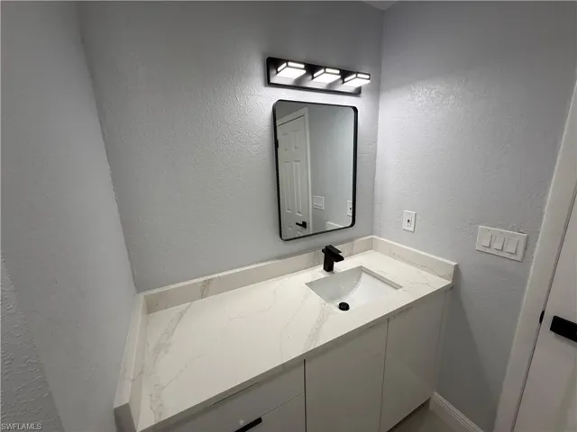 Bathroom with vanity and a textured wall